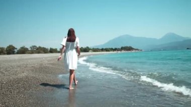 Dalgalanan denizin kenarında dans eden mutlu genç kadın