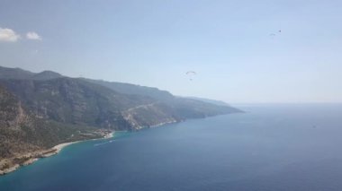 Paragliderler tatil köyünde deniz ve sahil üzerinde uçuyorlar.