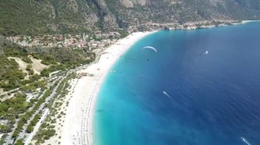 Paragliderler tatil köyünde deniz ve sahil üzerinde uçuyorlar.