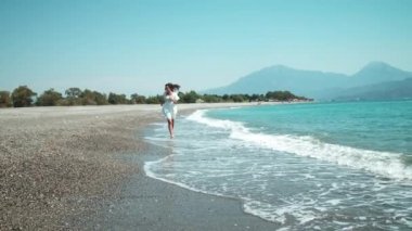 Dalgalanan denizin kenarında dans eden mutlu genç kadın