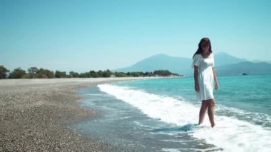 Dalgalanan denizin kenarında dans eden mutlu genç kadın