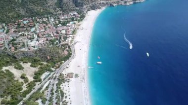 Paragliderler tatil köyünde deniz ve sahil üzerinde uçuyorlar.