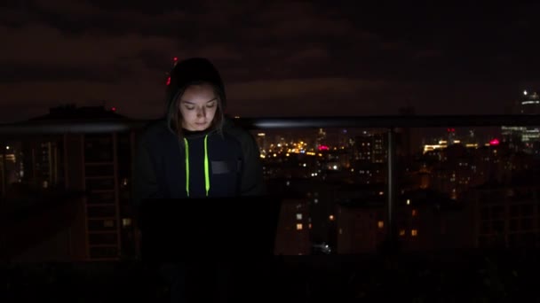 Mujer joven usando el ordenador portátil en el balcón por la noche — Vídeos de Stock