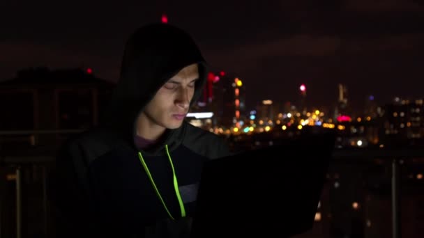 Genç adam geceleri balkonda dizüstü bilgisayar kullanıyor. — Stok video