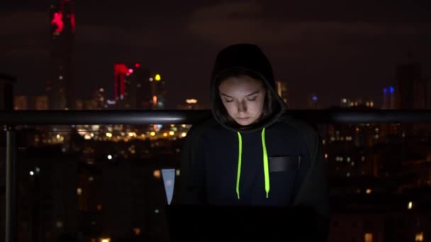 Genç bir kadın geceleri balkonda dizüstü bilgisayar kullanıyor. — Stok video