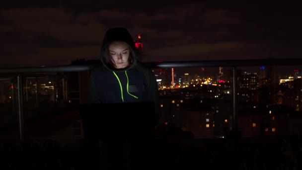 Молодая женщина использует ноутбук на балконе ночью — стоковое видео