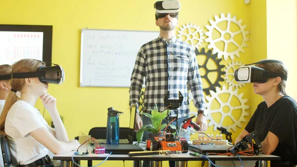 Young students and teacher with robot in classroom Stock Photo