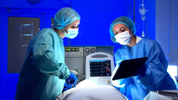 Ärztinnen operieren im Operationssaal Stockbild