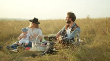 Piknik sırasında ailesi için gitar çalan adam.