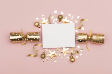 Altın Noel fişeği ile boş bir beyaz etiket. pastel pembe bir arka plan üzerinde lüks altın şenlikli kraker