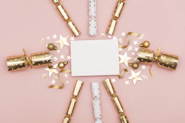 Altın Noel fişeği ile boş bir beyaz etiket. pastel pembe bir arka plan üzerinde lüks altın şenlikli kraker