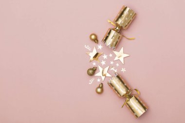 Noel kraker. pastel pembe bir arka plan üzerinde lüks altın şenlikli kraker