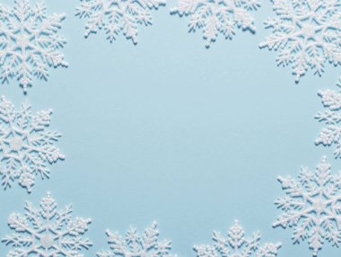 Pastel mavi zemin üzerine beyaz glitter kar tanesi kompozisyon