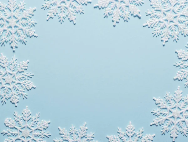Pastel mavi zemin üzerine beyaz glitter kar tanesi kompozisyon
