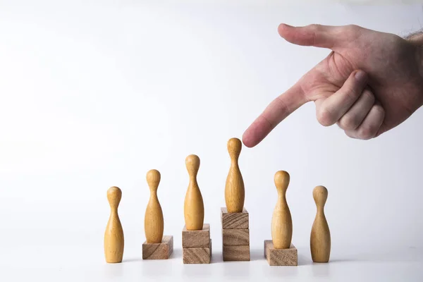 Hand selecting a wooden figure. Business leadership concept