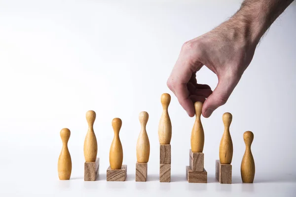 Hand selecting a wooden figure. Business leadership concept