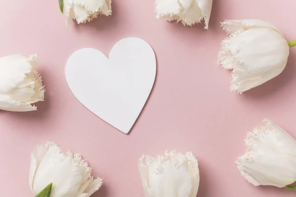 White flowers and hearts on a pastel pink background