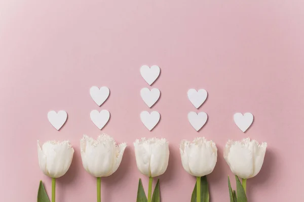 White flowers and hearts on a pastel pink background