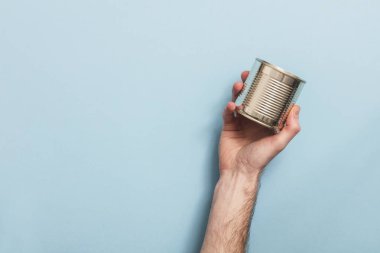 Boş metal teneke kutu mavi bir arka plan karşı geri dönüşüm tutan el