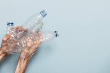 Mavi bir arka plan karşı geri dönüşüm boş plastik şişe tutan el