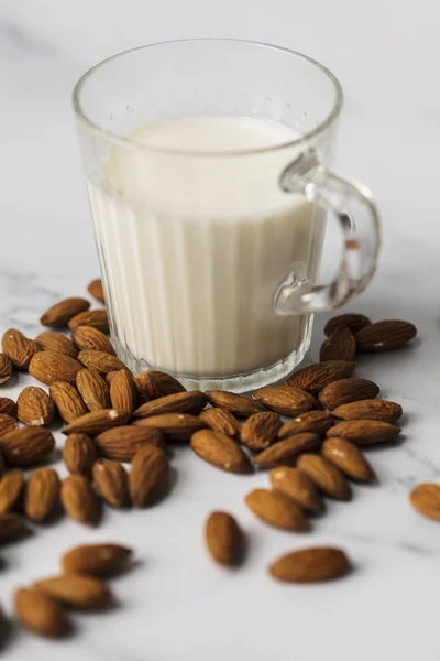 Susu almond dalam gelas yang dikelilingi oleh almond organik — Stok Foto