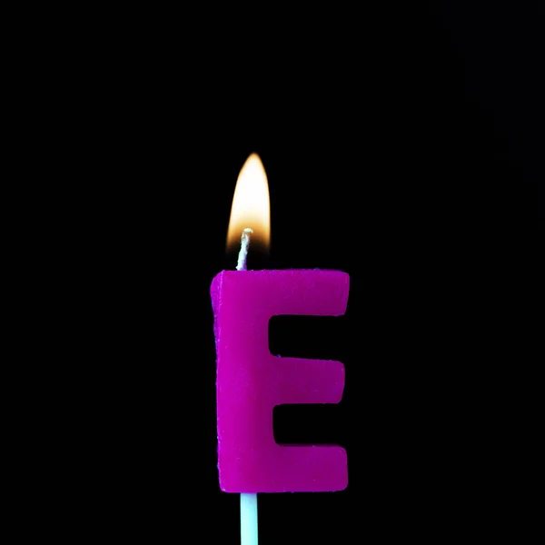 Carta E celebración vela de cumpleaños sobre un fondo negro — Foto de Stock
