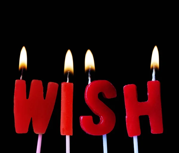 Deseo deletreado en velas de cumpleaños rojas sobre un fondo negro — Foto de Stock