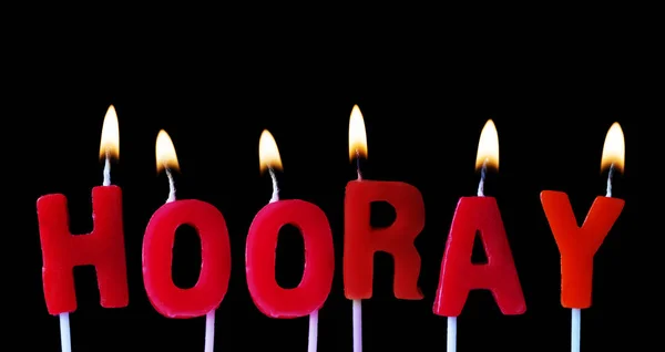 Hurra deletreado en velas de cumpleaños rojas sobre un fondo negro — Foto de Stock