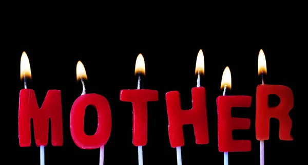 Mère épeler dans des bougies d'anniversaire rouges sur un fond noir — Photo