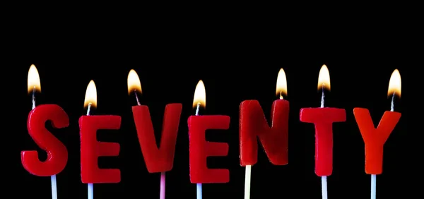 Setenta soletrado em velas de aniversário vermelhas contra um fundo preto — Fotografia de Stock