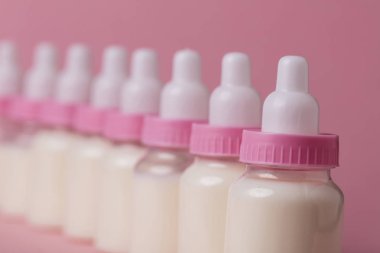 Bebek şişe pembe bir arka plan üzerinde süt dolu