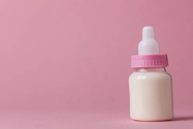 Bebek şişe pembe bir arka plan üzerinde süt dolu