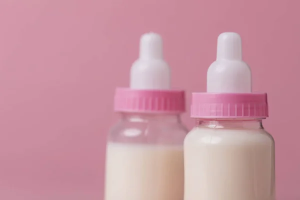 Baby bottle full of milk on a pink background — Stock Photo, Image