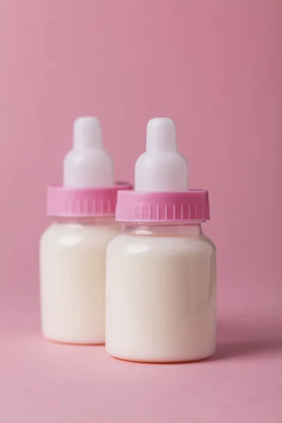 Biberón lleno de leche sobre un fondo rosa — Foto de Stock