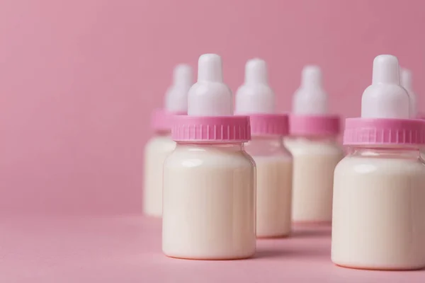 Bebek şişe pembe bir arka plan üzerinde süt dolu — Stok fotoğraf