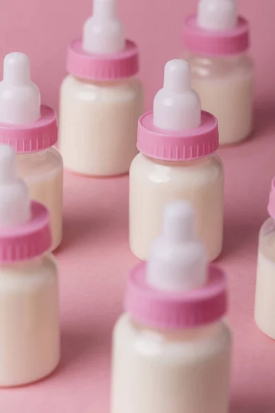 Biberón lleno de leche sobre un fondo rosa — Foto de Stock