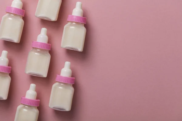 Garrafas de bebê com leite em um fundo rosa pastel — Fotografia de Stock