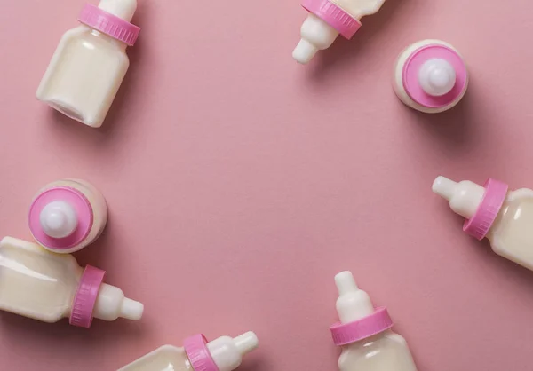 Biberones con leche sobre fondo rosa pastel — Foto de Stock