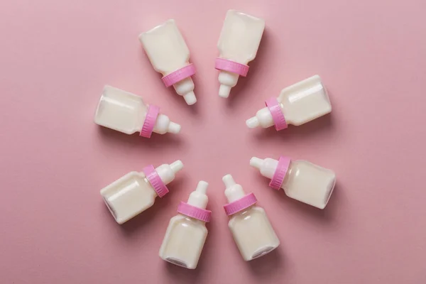 Biberones con leche sobre fondo rosa pastel — Foto de Stock