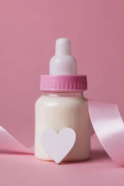 Kojenecká láhev na pastelově růžové pozadí. Nový přírůstek dítěte — Stock fotografie
