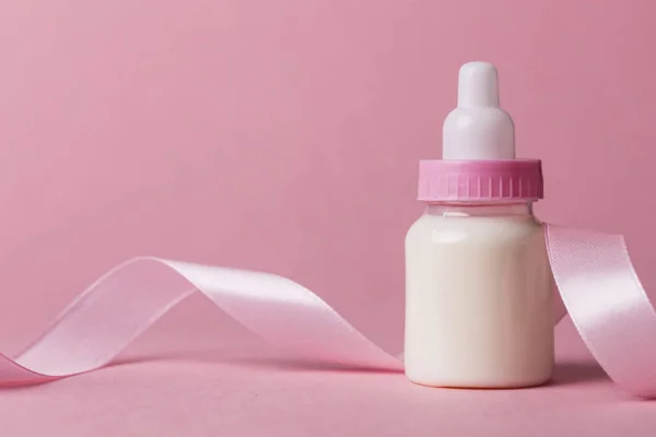 Biberón sobre fondo rosa pastel. Nueva llegada del bebé — Foto de Stock