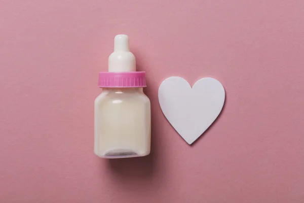 Babyfles op een pastel roze achtergrond. Nieuwkomer van de baby — Stockfoto