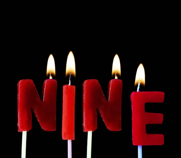 Nove incantesimi in candele di compleanno rosse su uno sfondo nero — Foto Stock