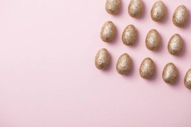 Altın yumurta pastel pembe arka plan üzerinde parıldayan. Mutlu Paskalya