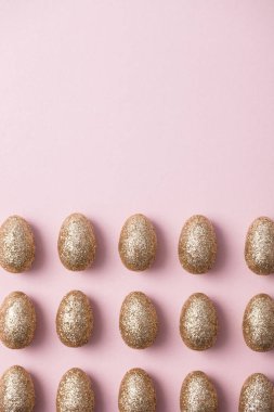 Altın yumurta pastel pembe arka plan üzerinde parıldayan. Mutlu Paskalya