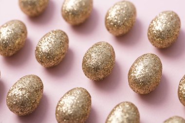 Altın yumurta pastel pembe arka plan üzerinde parıldayan. Mutlu Paskalya