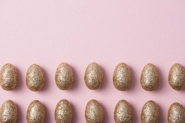 Altın yumurta pastel pembe arka plan üzerinde parıldayan. Mutlu Paskalya