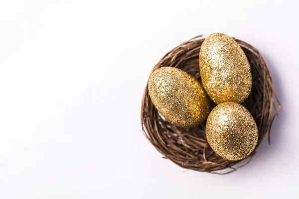 Goldene Glitzereier in einem Nest. Osterhintergrund. Finanzierungskonzept — Stockfoto