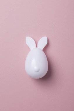 Pastel pembe bir arka plan üzerinde tavşan kulaklı Paskalya yortusu yumurta