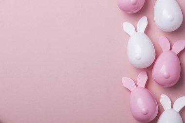 Paskalya yumurtaları pastel pembe bir arka plan üzerinde tavşan kulaklı